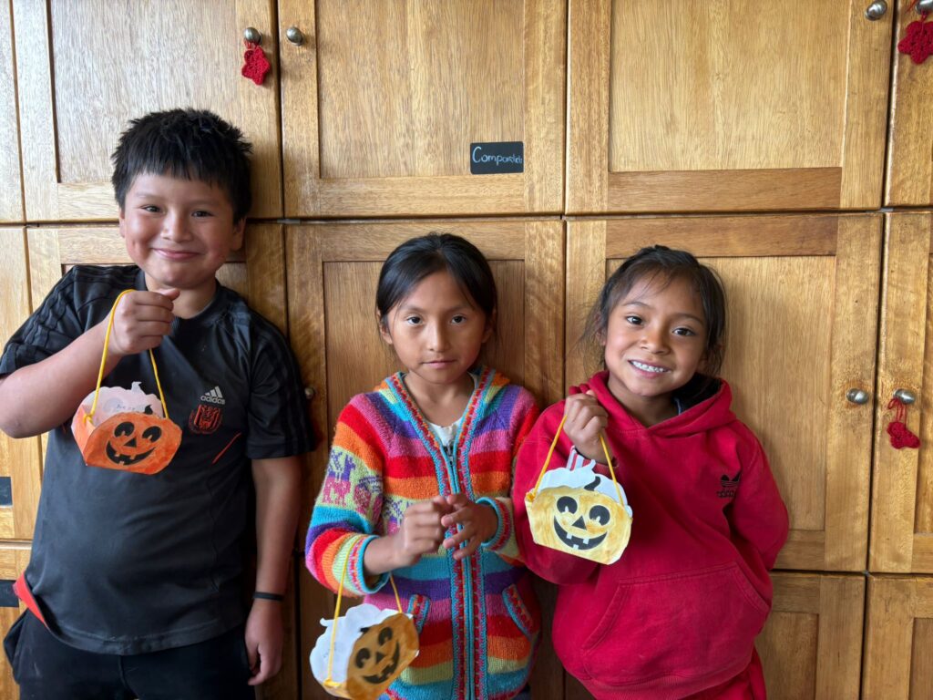 Kinderen staan naast elkaar met hun zelf gemaakt halloween kunstwerkje.
