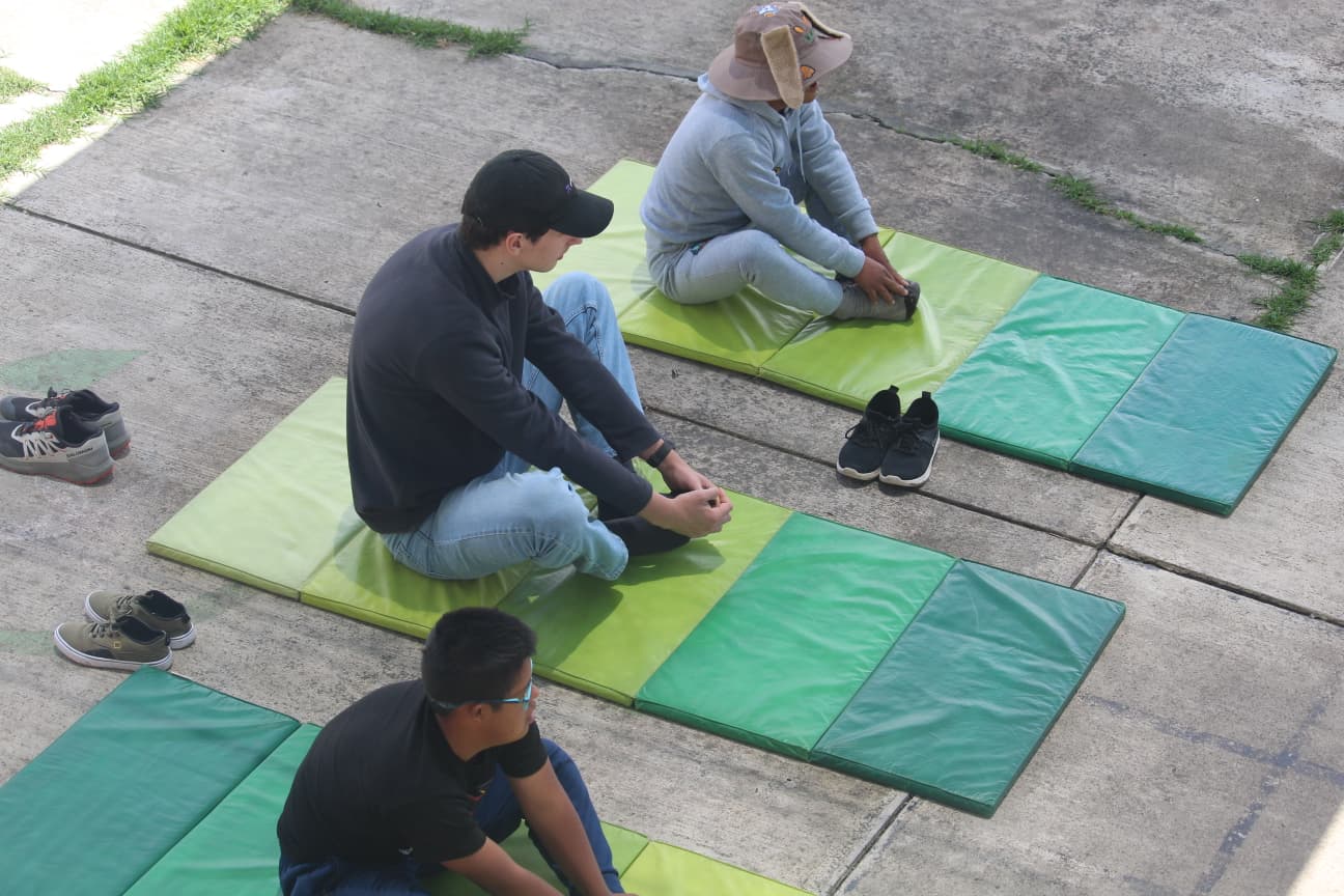 Een vrijwilliger doet samen met 2 leerlingen met het syndroon van Down een yoga-oefening